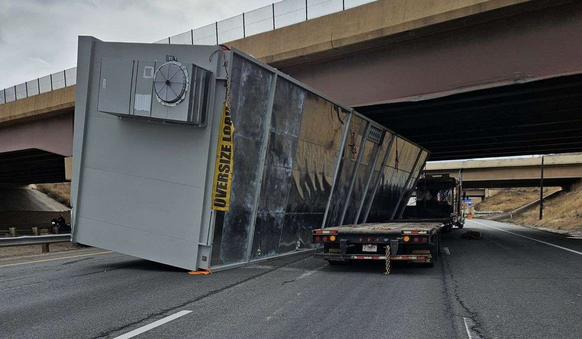 Semi truck with an oversized construction trailer stuck under Colorado bridge